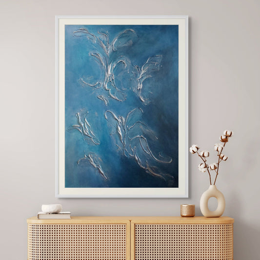 Framed blue abstract limited edition print artwork on a wall above a wooden cabinet with decorative items.