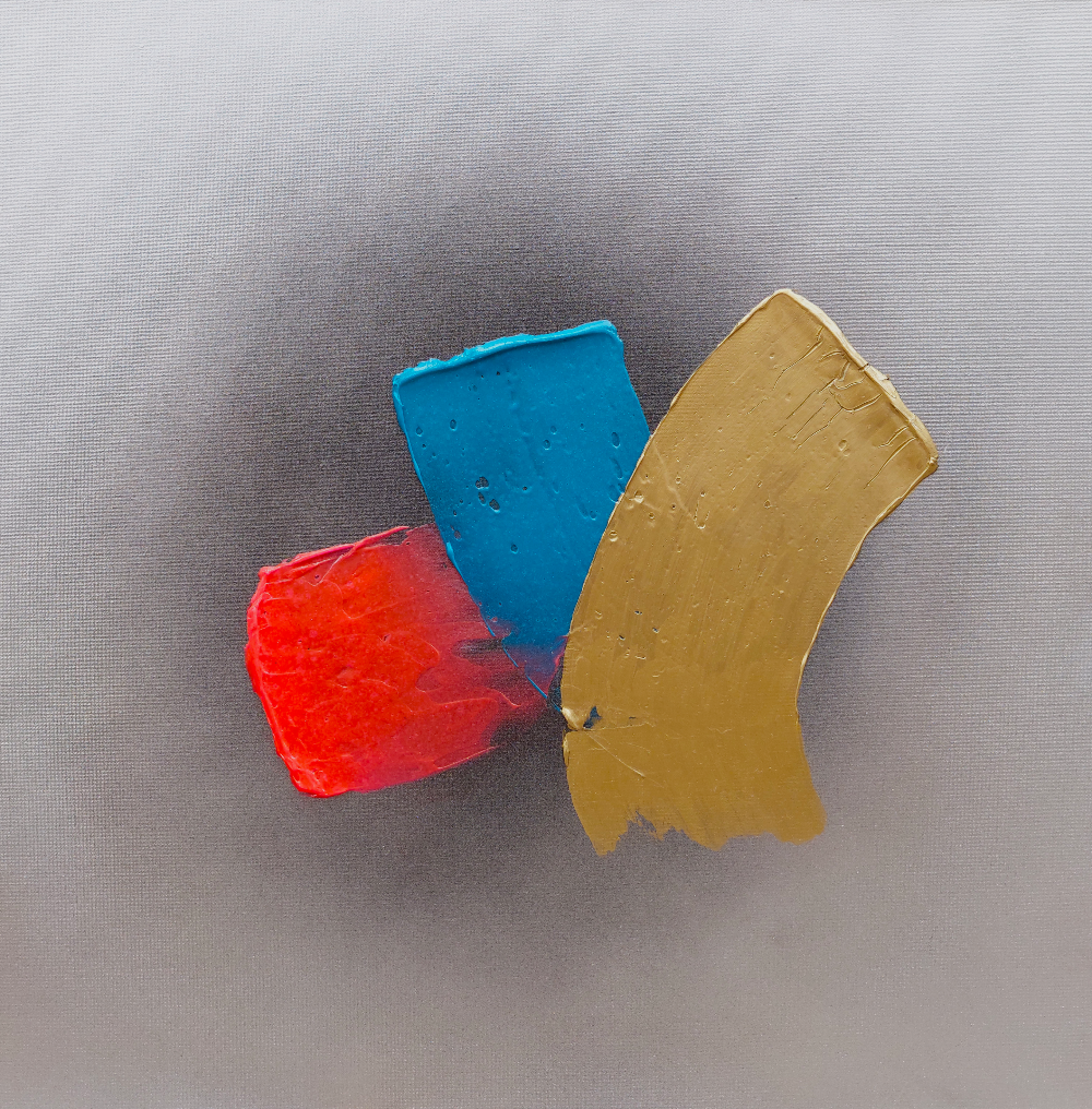 Three colorful clay blocks (red, blue, yellow) on a gray background