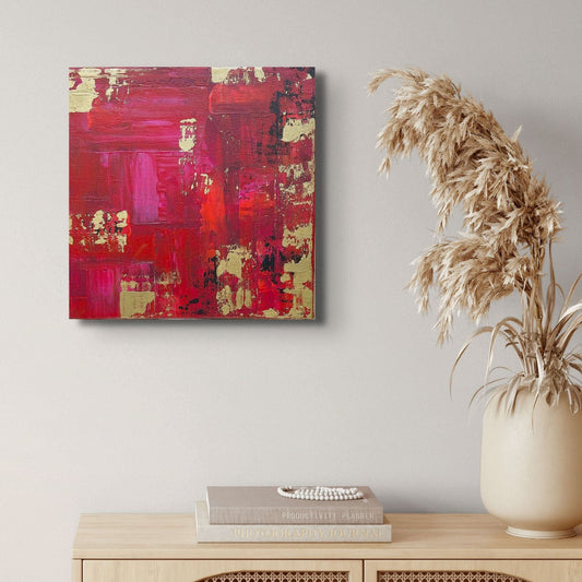 Abstract red and gold painting on a wall above a wooden cabinet with books and a vase. samhain no.1