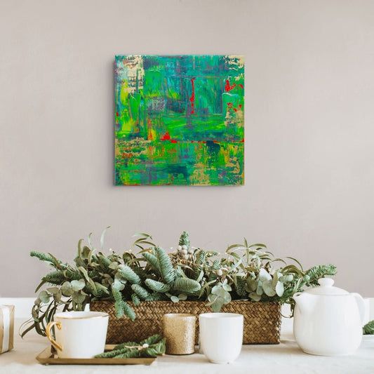 An abstract green and teal canvas painting with red accents hangs on a light beige wall above a styled tabletop with potted green plants, white ceramic cups, and a white teapot. samhain no 3 original canvas art by julie bevan