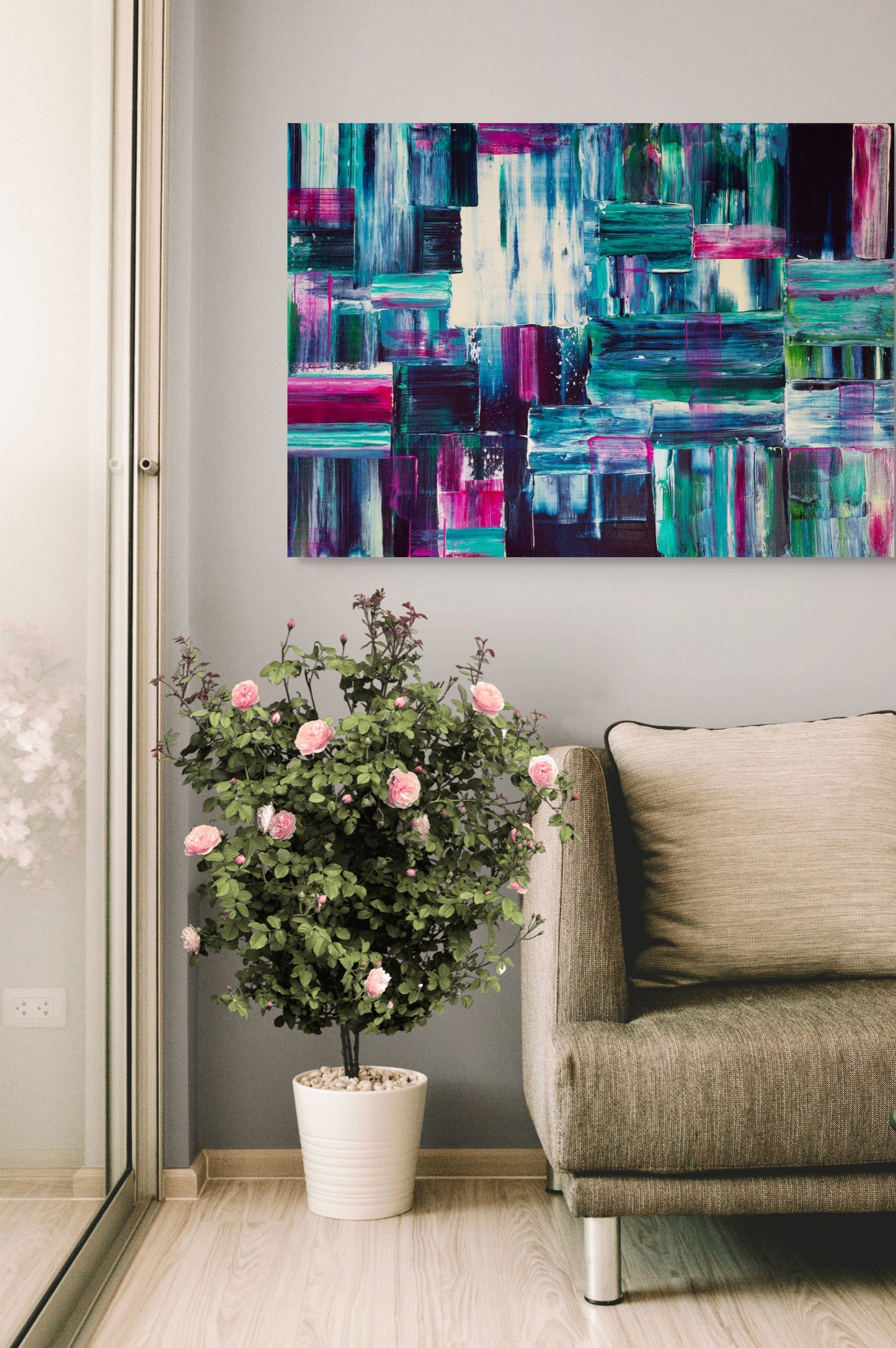 Living room with a colorful abstract painting, potted plant, and beige sofa.