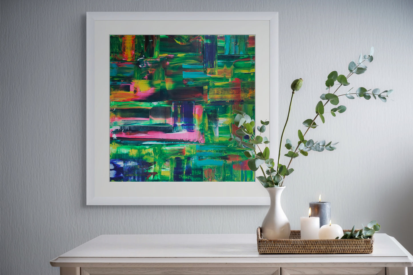 Abstract painting on a wall above a table with decor items