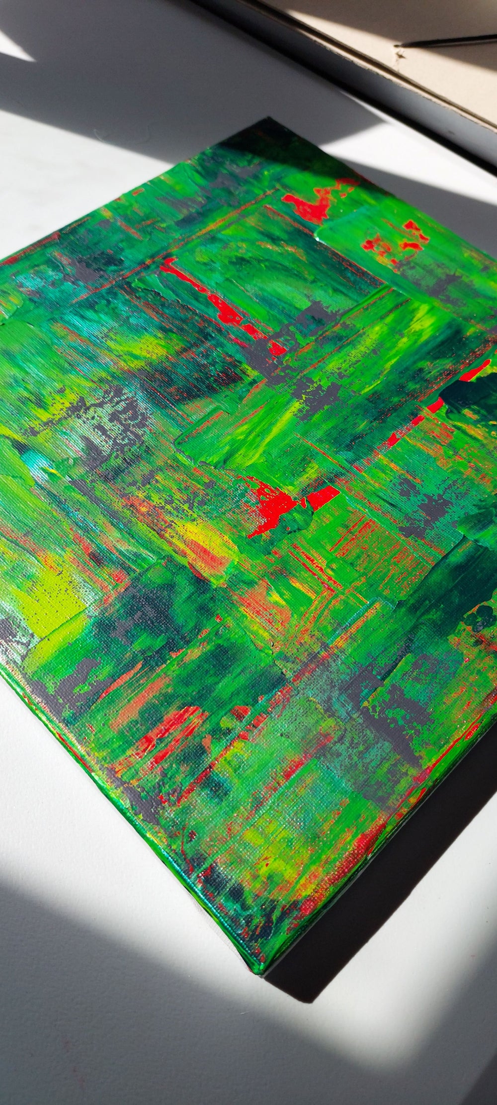 Abstract painting with green, red, and blue hues on a white surface