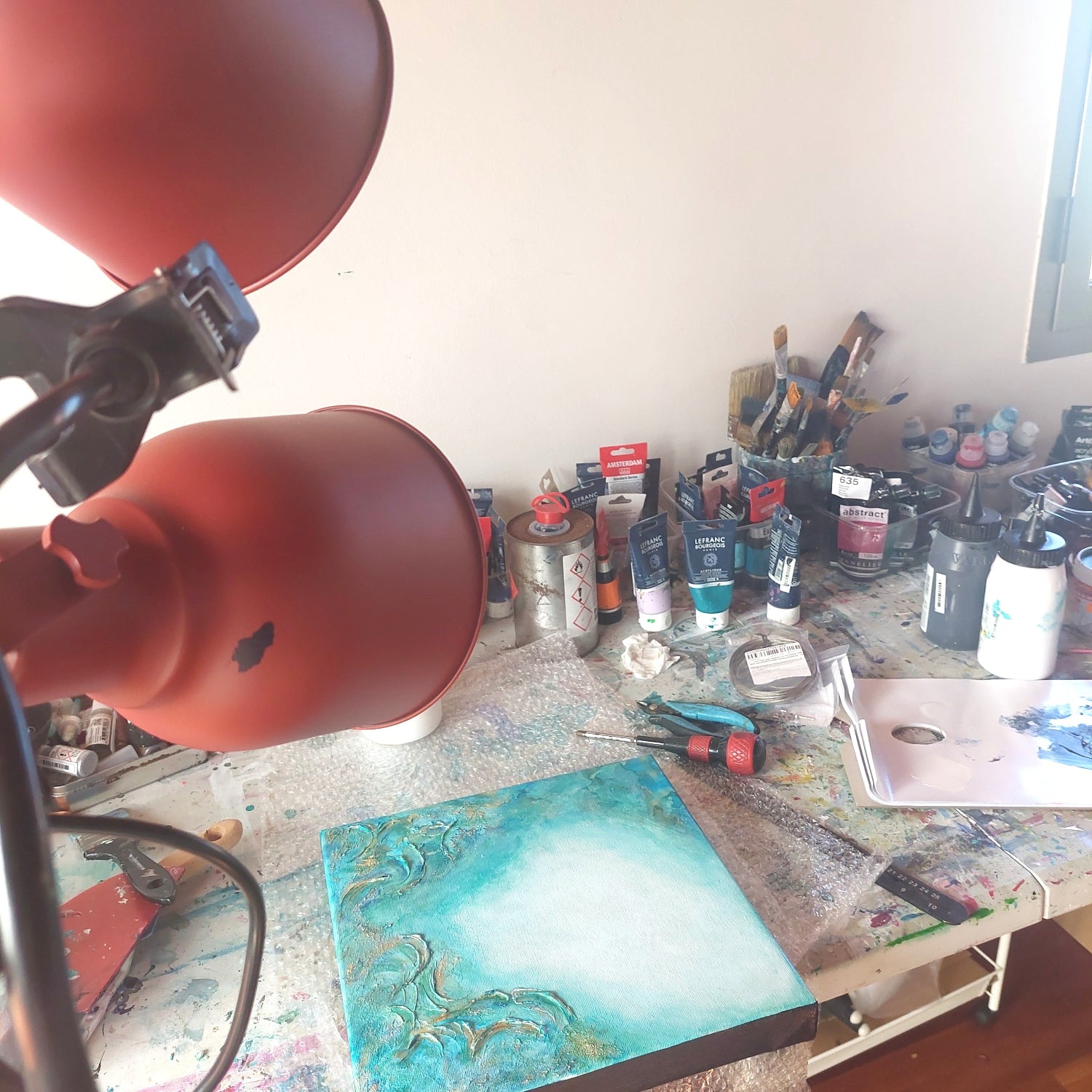 Artistic workspace with painting supplies and a lamp on a table. From the Depths, Original Canvas Painting