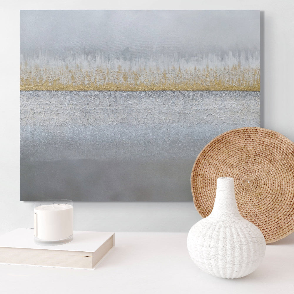 Abstract painting with a gold stripe on a white wall, accompanied by a woven basket and decorative items. Earthed original canvas painting by Julie Bevan.