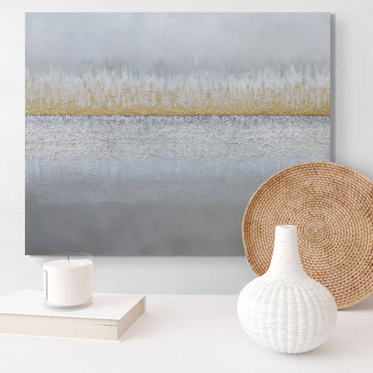 Abstract painting with a gold stripe on a white wall, accompanied by a woven basket and decorative items. Earthed original canvas painting by Julie Bevan.