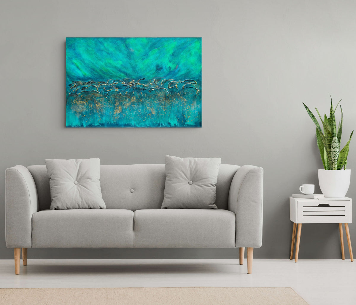 An abstract canvas painting with vibrant teal, turquoise, and gold brushstrokes, displayed on a light gray wall above a modern light gray sofa in a styled living room setting. Equinox, Original Canvas Painting by Julie Bevan