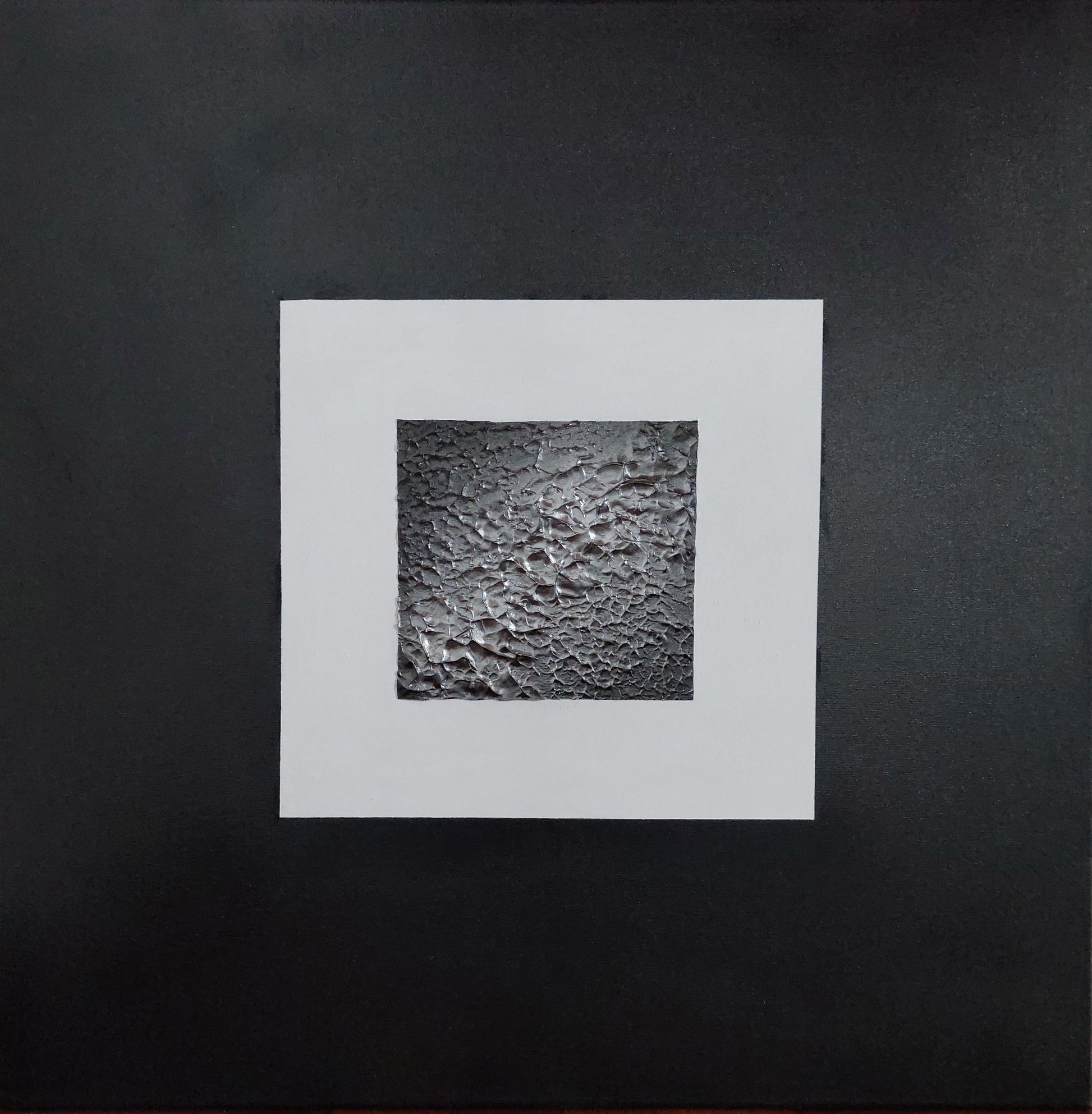 Square white frame with textured black center on a black background