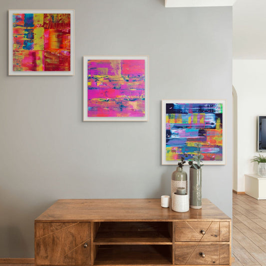 Wooden entertainment console with decorative items against a wall with three fine art colourful prints, flurry, Denim and Midnight By Julie Bevan Art