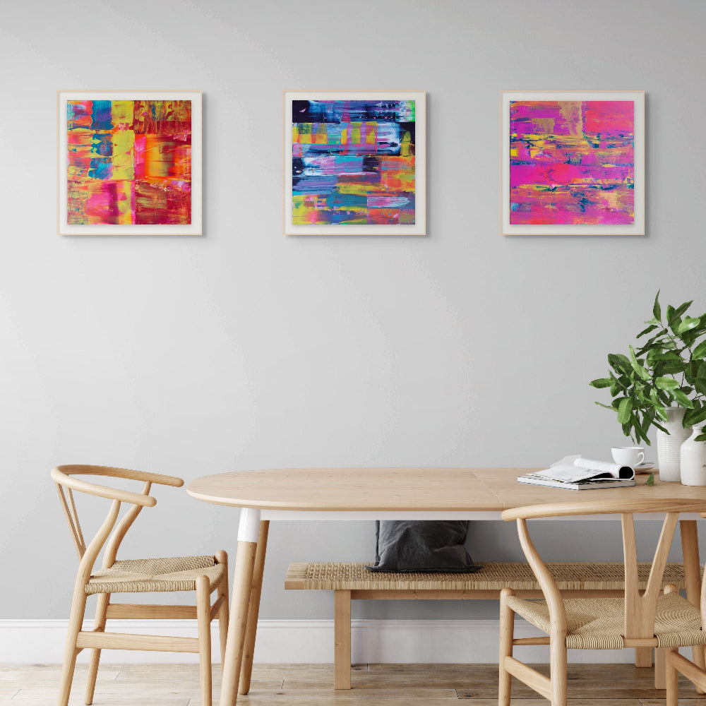 Dining room with a wooden table and chairs, with three fine art colourful prints, flurry, Denim and Midnight By Julie Bevan Art