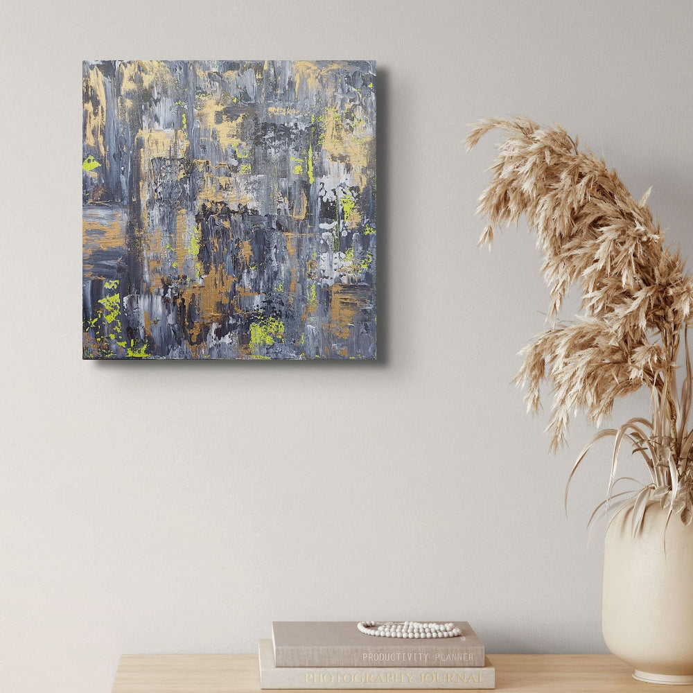 Abstract painting on a wall above a wooden cabinet with a vase and books.