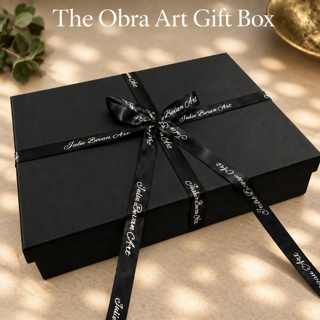 A dark black rectangular gift box tied with a black satin ribbon printed with the brand name 'Julie Bevan Art' in white script, set against a plain white background.