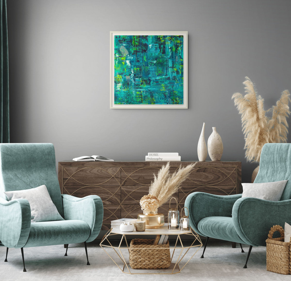 A framed abstract painting with teal, blue, and green brushstrokes hangs on a gray wall in a styled living room with two teal armchairs, a wooden sideboard, and decorative vases.