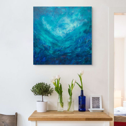 Abstract blue painting on a white wall above a wooden console table with decorative items. Swiss Blue Original Painting by Julie Bevan