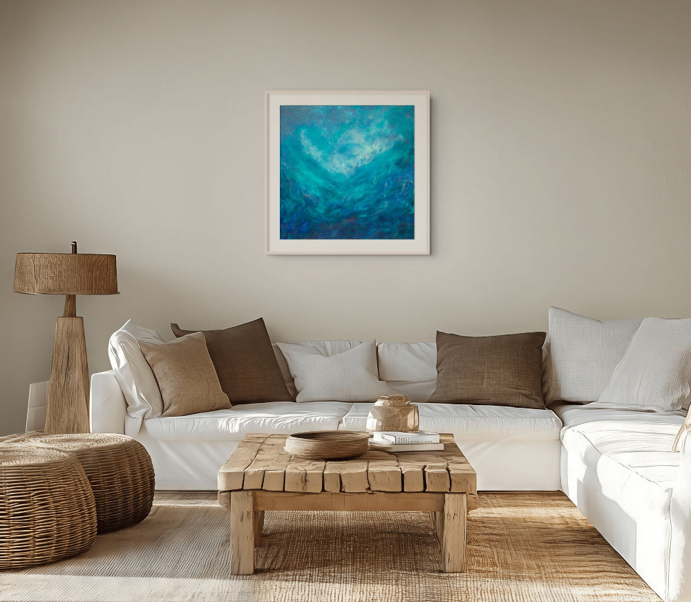 A framed abstract art print featuring swirling shades of blue and teal, displayed on a beige wall above a white sectional sofa in a modern, neutral-toned living room.