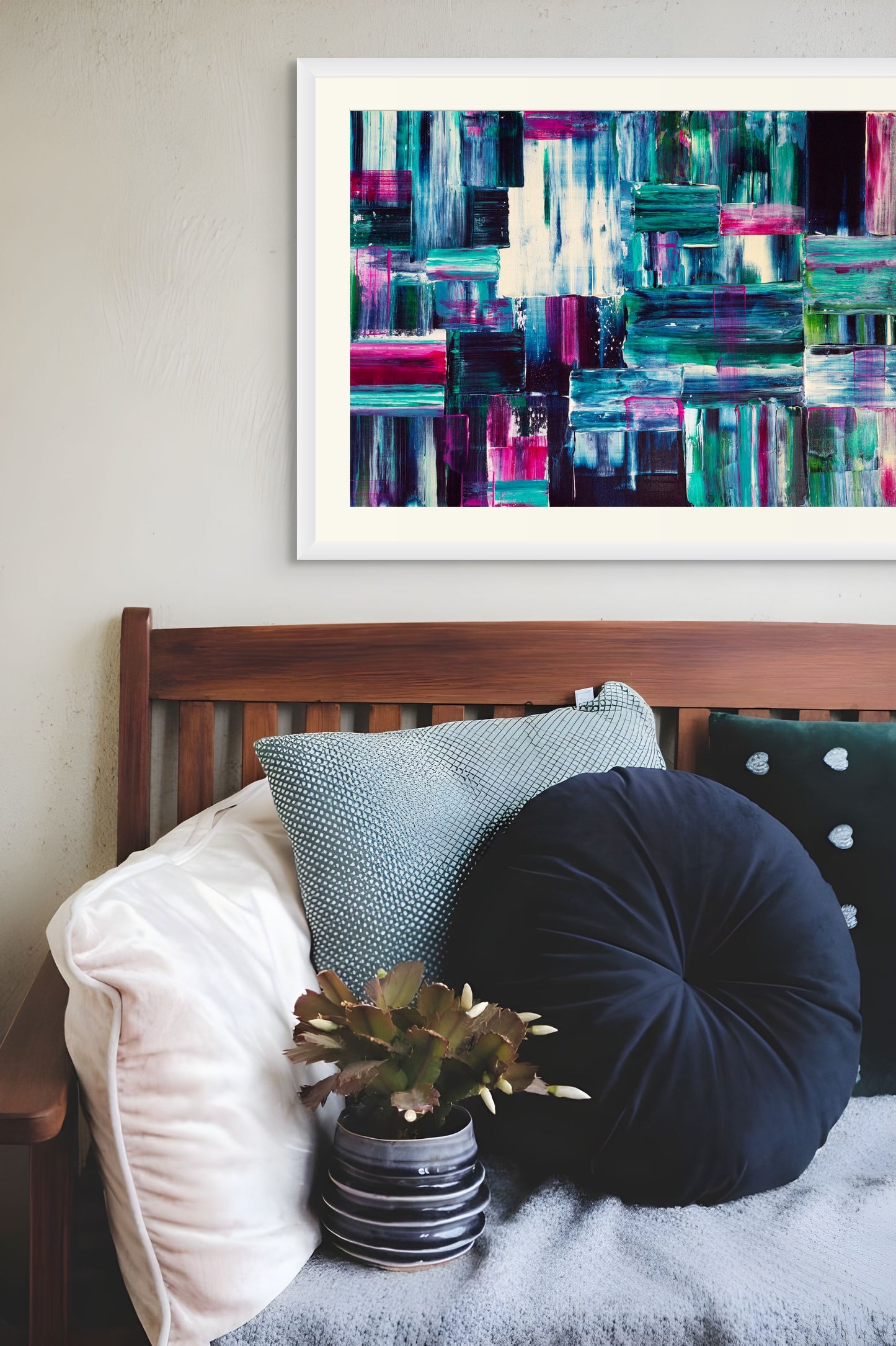 Framed abstract art above a couch with decorative pillows and a plant.