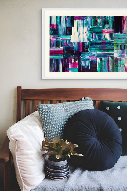 Framed abstract art above a couch with decorative pillows and a plant.