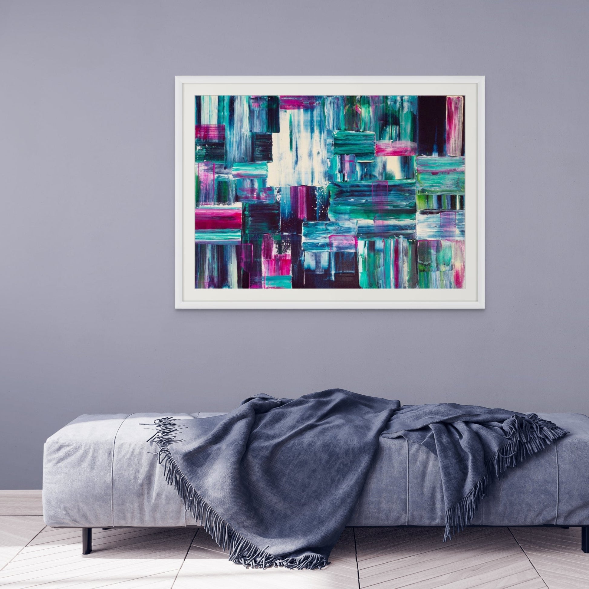 Abstract art print on a gray wall above a gray sofa with a blue blanket.