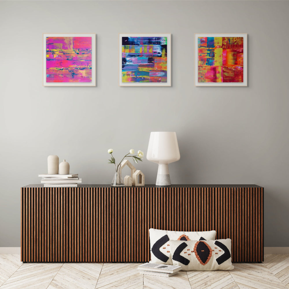 Modern interior with a wooden console table, decorative pillows, with three fine art colourful prints, flurry, Denim and Midnight By Julie Bevan Art